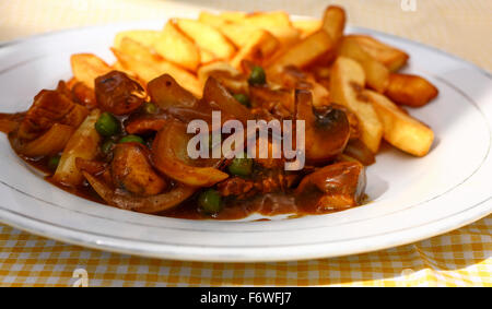 Sauté de poulet au curry et frites sur une nappe jaune vérifié Banque D'Images