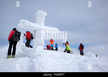 Groupe de personnes ski debout sur le sommet du Monte Amaro avec croix couverte de neige, Monte Amaro, Majella, Abruzz Banque D'Images