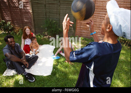 Séance de groupe famille multiraciale et jouant dans le jardin, Banque D'Images