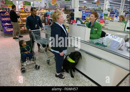 Femme avec une déficience visuelle et son chien-guide à la caisse 24 dans un supermarché, Banque D'Images