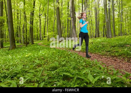 Young woman jogging dans une forêt de hêtres, Parc National, Hainich Thuringe, Allemagne Banque D'Images
