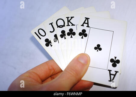 Une main tenant une quinte flush de clubs cartes contre un fond blanc. Banque D'Images