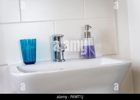 Distributeur de savon et de verre sur un lavabo dans une salle de bains de style contemporain. Banque D'Images