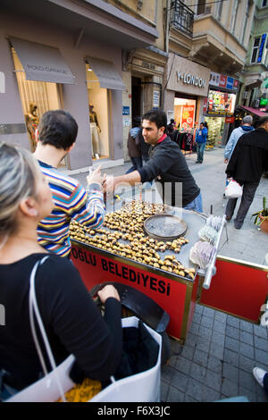 Châtaignes grillées chaudes sont un snack populaire le long de la rue piétonne commerçante animée Istiklal Caddesi, quartier de Beyoglu. Banque D'Images