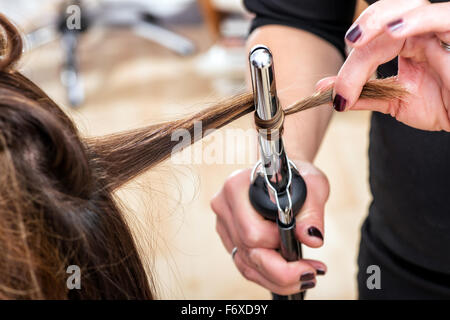 Hairstylist à l'aide d'un fer à friser à ferme anglaises, vue rapprochée de la main Banque D'Images