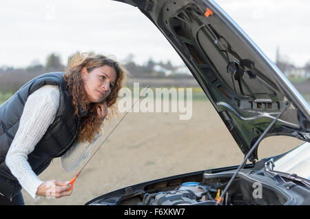 La femme voiture tombe en panne et elle est de contrôler le niveau d'huile Banque D'Images