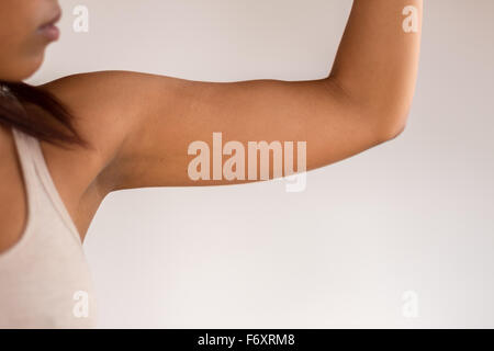 Close up Athletic Jeune femme afro-américaine en montrant son muscle du bras contre mur blanc Arrière-plan. Banque D'Images
