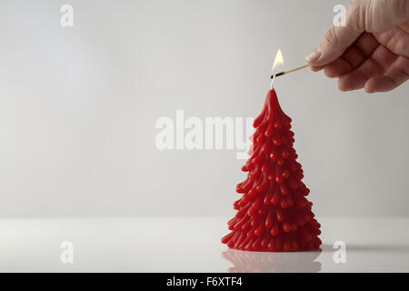 Mans hand holding a correspondre à l'éclairage d'une bougie dans la forme d'un arbre de Noël Banque D'Images