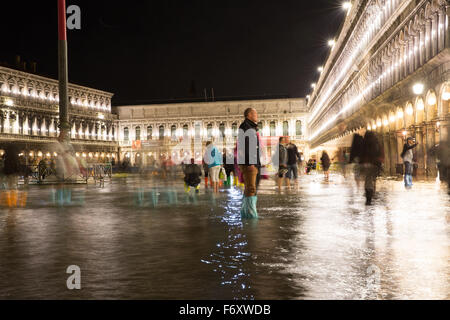 Inondations dans la place Saint-Marc, Venise, Italie. Les gens patauger dans l'inondation dans la nuit. Longue Exposition. Banque D'Images