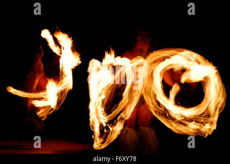 Deux danseurs de feu allumé en rotation des matraques dans la nuit après un luau Banque D'Images