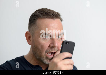 Surpris man looking at mobile phone Banque D'Images