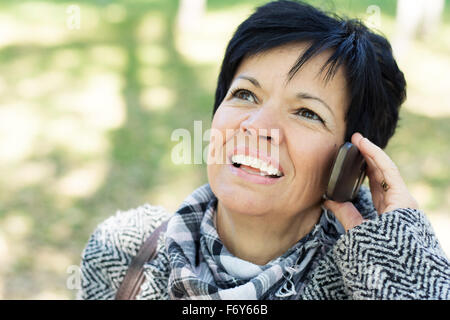 Belle femme d'âge moyen avec l'utilisation de la coupe sombre court in park Banque D'Images