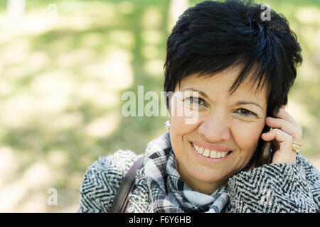 Belle femme d'âge moyen avec l'utilisation de la coupe sombre court in park Banque D'Images