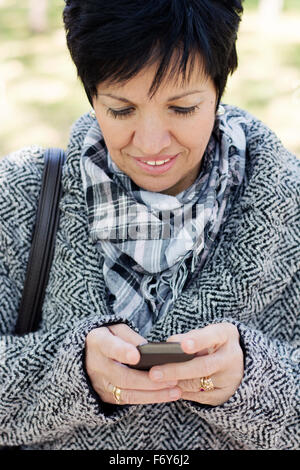 Belle femme d'âge moyen avec l'utilisation de la coupe sombre court in park Banque D'Images