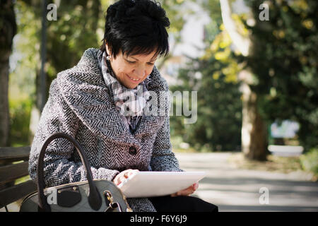 Belle femme d'âge moyen avec l'utilisation de la coupe sombre court in park Banque D'Images