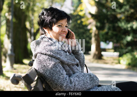 Belle femme d'âge moyen avec l'utilisation de la coupe sombre court in park Banque D'Images