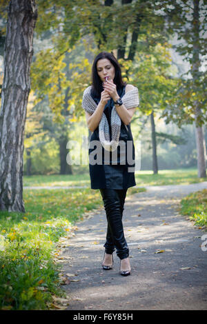 Belle black hair woman enjoying cigarette dans park Banque D'Images