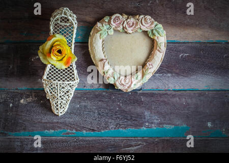 Des cadres photo et des fleurs dans des chaussures sur fond de bois. Banque D'Images