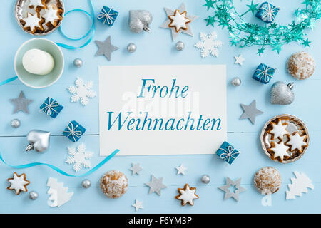 Fond de Noël, immersive, carte postale ou en-tête site web design avec les mots allemand Frohe Weihnachten sur table en bois bleu Banque D'Images