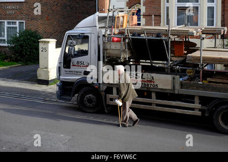 Homme âgé avec des bâtons de marche forcé de marcher autour d'un camion en stationnement obstruant la chaussée england uk Banque D'Images