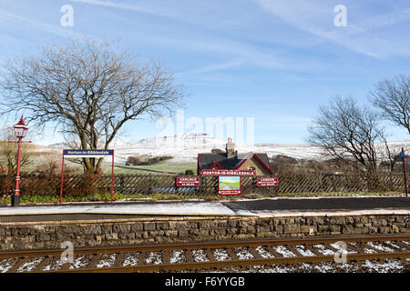 La gare de Horton Ribblesdale avec panneau à Carlisle et à Londres, avec un couvert de neige le Pen-y-ghent montagne derrière Banque D'Images