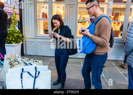 Paris, France, couple, touristes chinois, acheteurs, shopping dans Luxury Outlet Mall, Centre commercial, 'la Valleé Village', Marne-la Vallée, en banlieue, rue avec le parc de vente au détail de sacs à provisions Banque D'Images