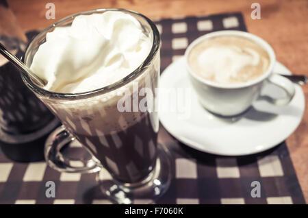 Verre de chocolat chaud et une tasse de cappuccino, debout sur une table Banque D'Images