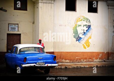 Vintage bleu et blanc avec voiture garer à côté du Che Guevara murale sur un jour de pluie à La Havane Cuba Banque D'Images