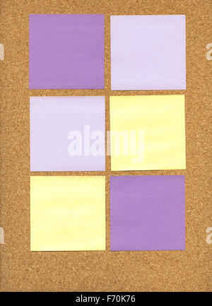 Purple and yellow sticky notes sur un tableau de liège Banque D'Images