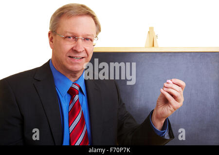 Enseignant heureux debout devant un tableau noir Banque D'Images