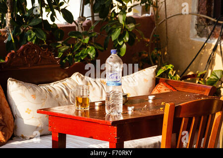 Santorin. Still Life, Close up de table dehors taverne grecque, avec de l'eau bouteille et verre chope à moitié plein avec de la bière et des miettes. Le lendemain matin. Banque D'Images