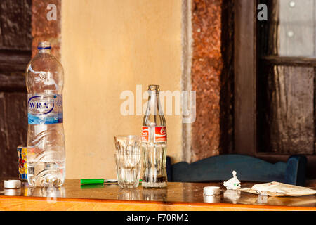 Santorin. Still Life, Close up de table dehors taverne grecque, avec une bouteille d'eau, bouteille de coca-cola, des verres et des miettes sur. Le lendemain matin. Banque D'Images