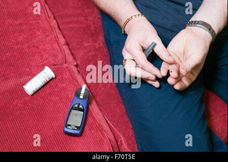 L'homme avec le diabète à l'aide d'un moniteur pour vérifier sa lecture de glucose de sang, Banque D'Images