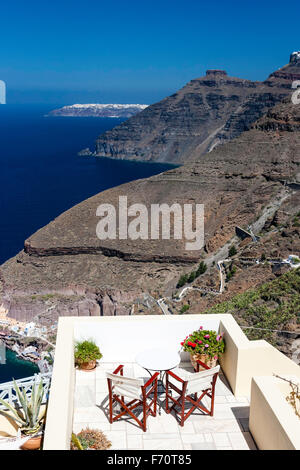 Santorin, Fira. Balcon, terrasse, avec deux chaises de bois et toile avec plus de table à la vue des côtes, la caldeira et la mer. Banque D'Images