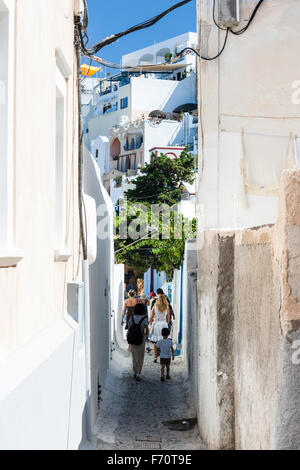 Santorin. Les touristes en se promenant dans la rue pavées typiques avec de grands murs blancs sur les deux faces, dans le vieux centre-ville de Fira. Banque D'Images