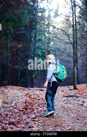 Portrait d'un garçon à l'extérieur de marche dans une forêt - se promener le long du chemin de la forêt d'automne Banque D'Images