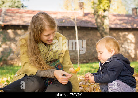 Maman blonde joue avec sa douce fille d'un an dans le parc Banque D'Images