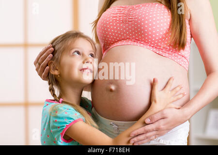 Happy kid girl hugging pregnant mother Banque D'Images