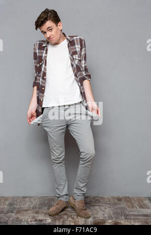 Portrait d'un homme montrant ses poches vides sur gris bakground Banque D'Images