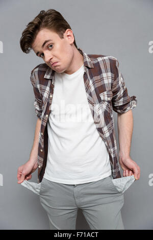 Portrait d'un homme triste présentant ses poches vides sur gris bakground Banque D'Images