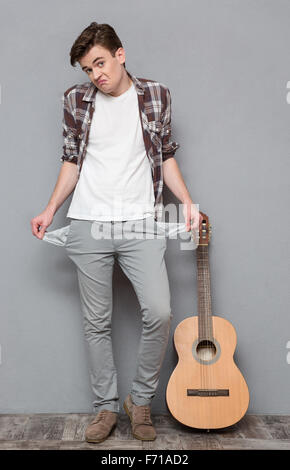 Portrait d'un jeune homme présentant ses poches vides sur gris bakground Banque D'Images