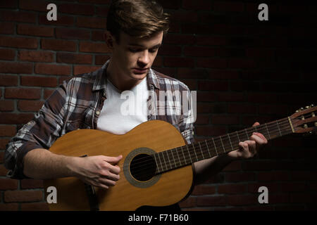 Beau Beau jeune guitariste timide en chemise à carreaux playing acoustic guitar Banque D'Images