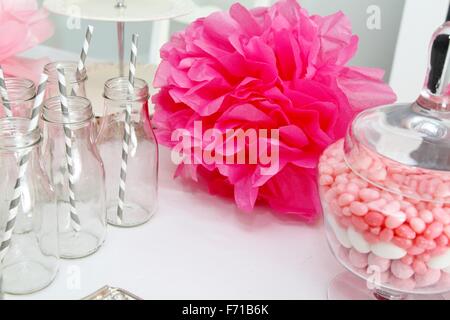 Célébration avec pompons rose, jelly beans et des bouteilles avec des pailles gris Banque D'Images