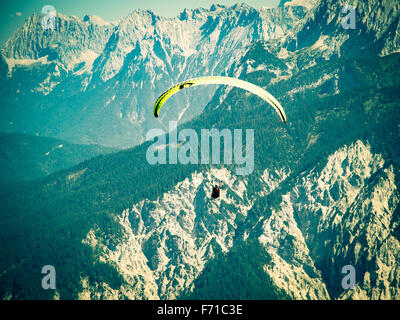 Vol en parapente sur la haute et solide gamme de montagnes des Alpes. Traitement croisé tonifié et filtrée stylisé Instagram stock photo Banque D'Images