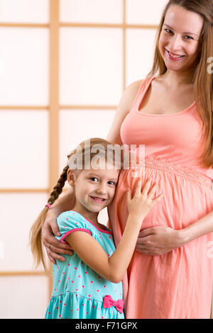 Happy kid girl hugging pregnant mother's belly Banque D'Images