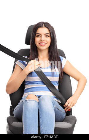 Studio shot verticale d'une jeune femme assise sur un siège de voiture fixé à l'aide d'une ceinture de sécurité isolé sur fond blanc Banque D'Images