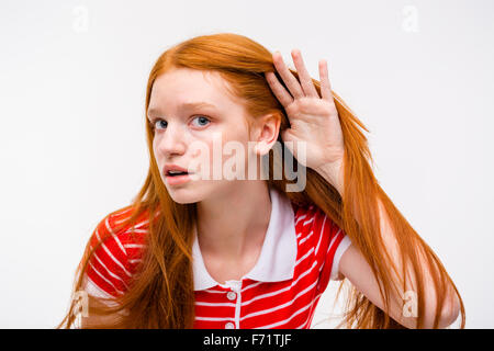 Jeune femme séduisante curieux avec de beaux longs cheveux rouges t-shirt à rayures en essayant d'écouter les rumeurs Banque D'Images