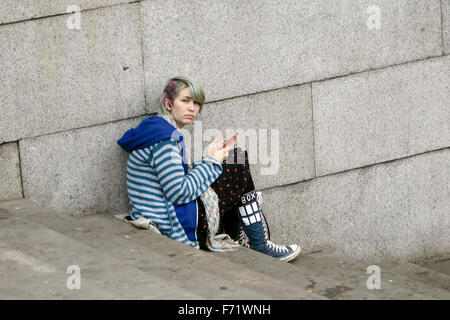 Young adult using cell phone in Trafalgar Square London Banque D'Images