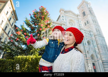 Mère et fille excité pointant sur quelque chose alors qu'il se tenait près de l'arbre de Noël et Duomo de Florence, en Italie. La famille moderne Banque D'Images