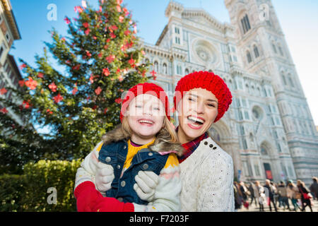 Portrait of smiling mother and daughter standing in front of Christmas Tree près du Dôme de Florence, en Italie. La famille moderne bénéficiant d'une s Banque D'Images